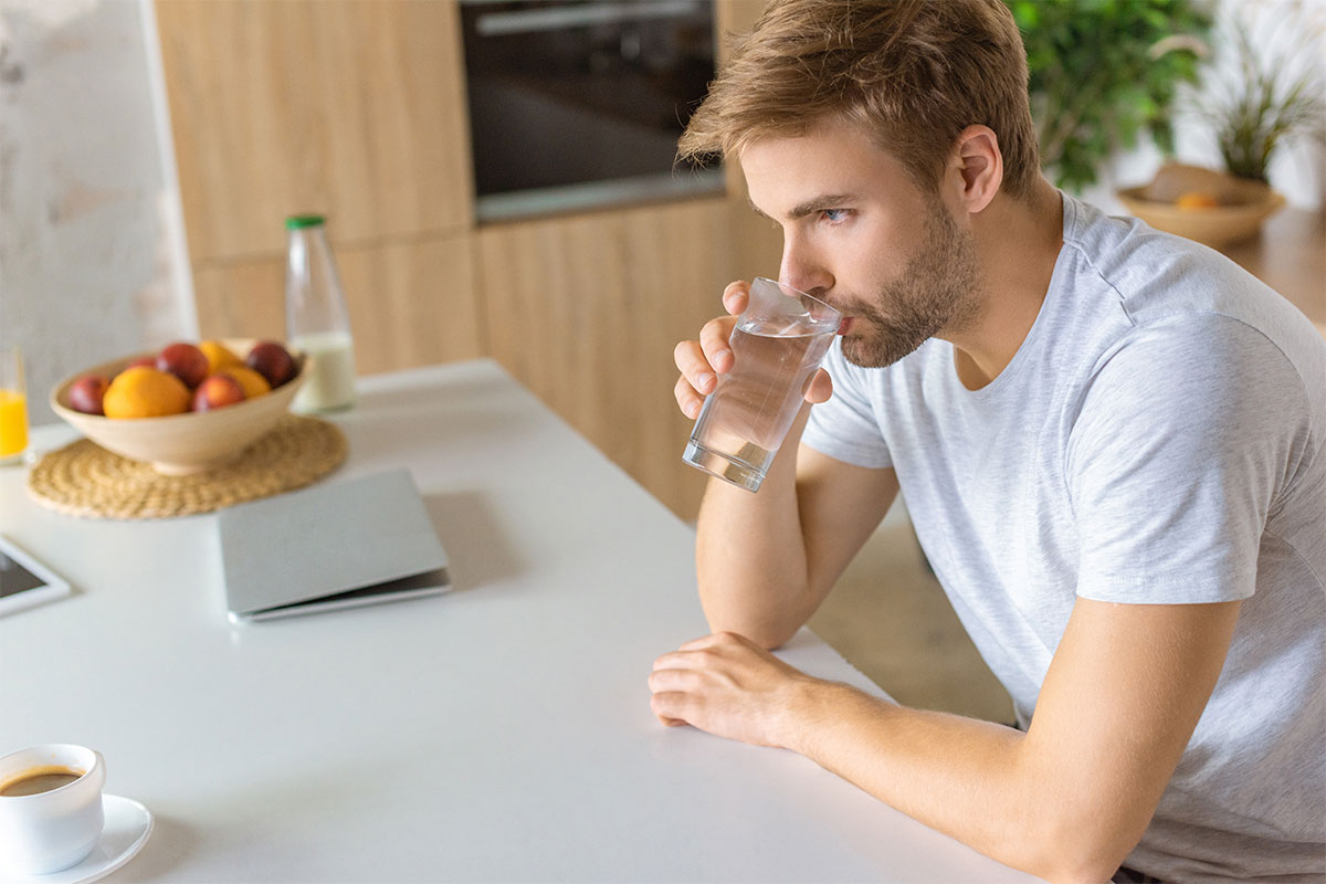 Man drinking glass of water in the kitchen